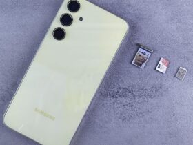 Smartphone ao lado de bandeja, cartão SIM e cartão de memória sobre uma superfície cinza.