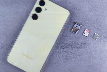 Smartphone ao lado de bandeja, cartão SIM e cartão de memória sobre uma superfície cinza.