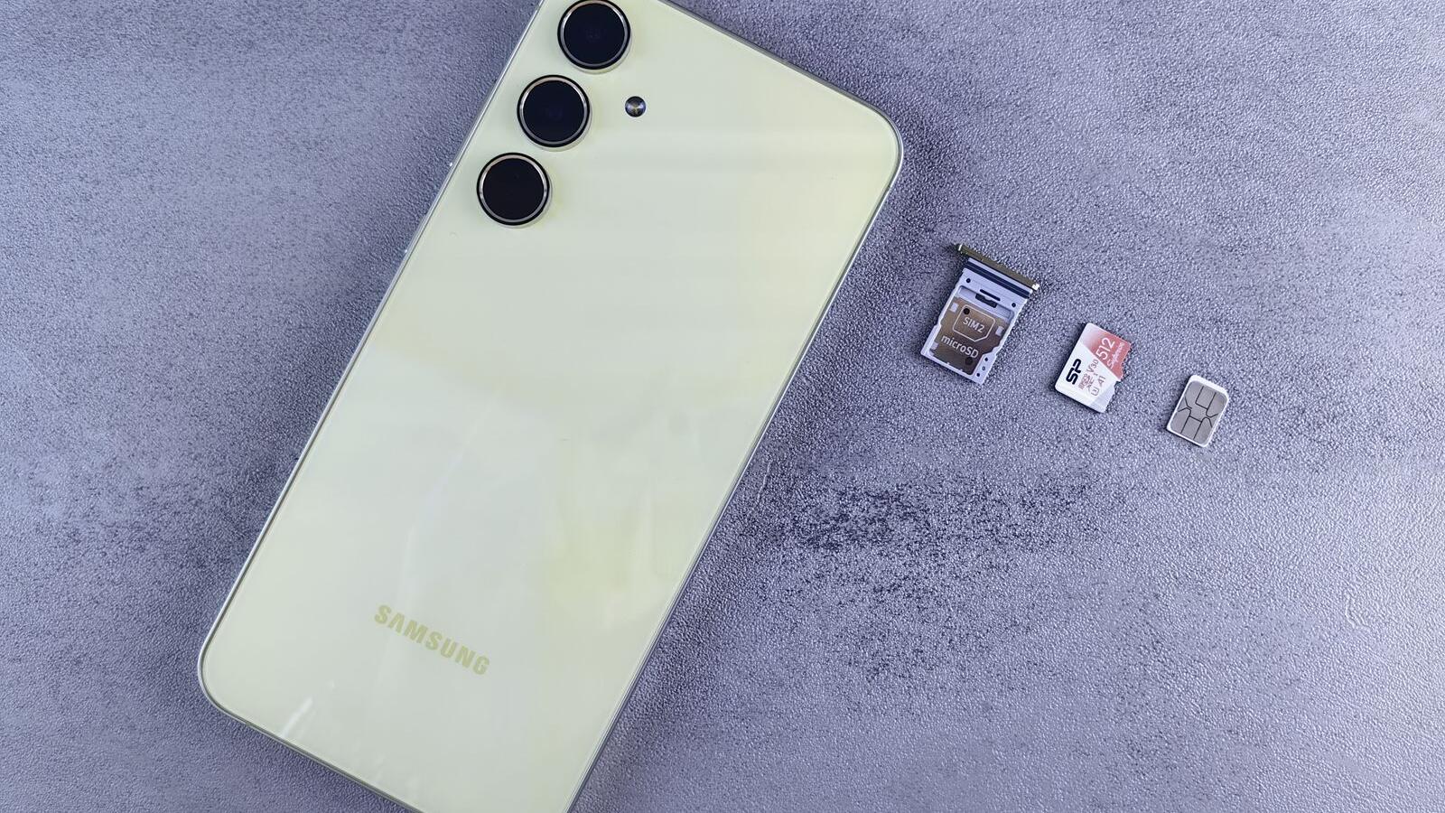 Smartphone ao lado de bandeja, cartão SIM e cartão de memória sobre uma superfície cinza.