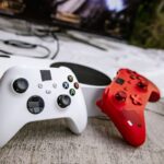 Dois comandos de videojogos junto a uma consola e um televisor