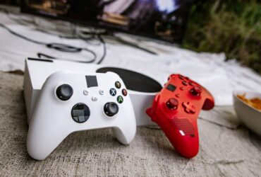 Dois comandos de videojogos junto a uma consola e um televisor