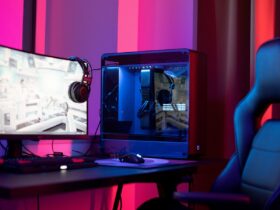 Computador gaming com monitor, auscultadores e cadeira iluminados por luzes azuis e vermelhas.