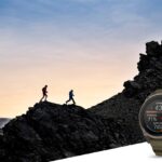Relógio Garmin Enduro 4 em vista frontal sobre fundo de montanha, com o ecrã a mostrar um mapa de percurso.