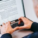 Pessoa digita em um notebook com um documento aberto na tela.
