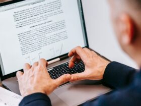 Pessoa digita em um notebook com um documento aberto na tela.