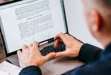 Pessoa digita em um notebook com um documento aberto na tela.