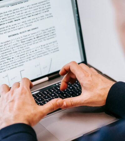 Pessoa digita em um notebook com um documento aberto na tela.