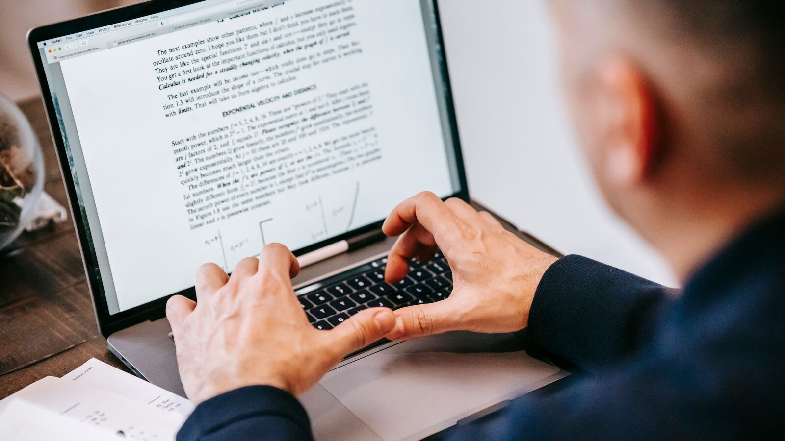 Pessoa digita em um notebook com um documento aberto na tela.