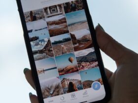 Mão segura um telemóvel que mostra uma grelha de fotografias no ecrã.