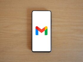 Telemóvel sobre uma mesa de madeira mostra o logótipo do Gmail no ecrã.