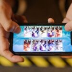 Mãos seguram um smartphone na horizontal durante uma sessão de jogo móvel.