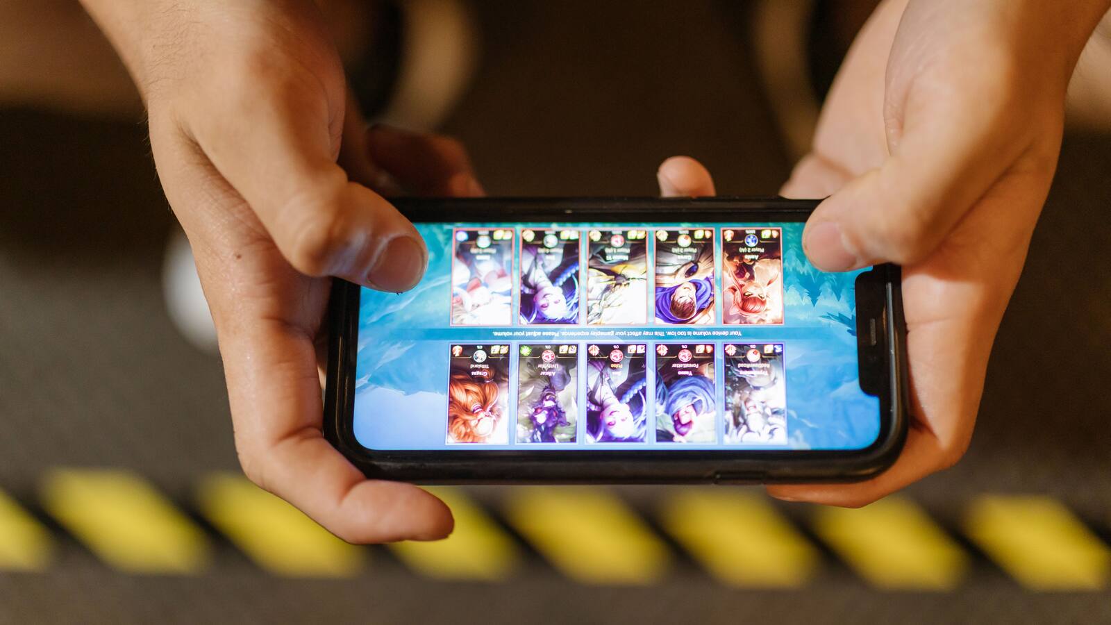 Mãos seguram um smartphone na horizontal durante uma sessão de jogo móvel.