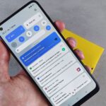 Mão segura um telemóvel Android com o painel de notificações aberto.