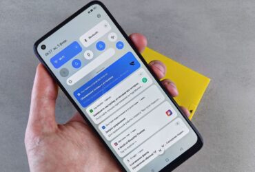 Mão segura um telemóvel Android com o painel de notificações aberto.