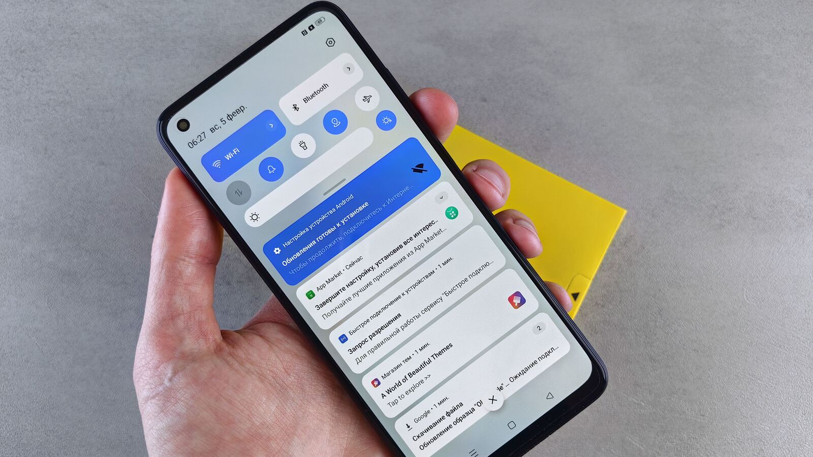Mão segura um telemóvel Android com o painel de notificações aberto.