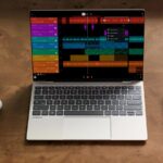 Googlebook e telemóvel Android lado a lado numa mesa, ambos com a mesma aplicação de produção musical aberta.