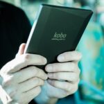 Pessoa segura um leitor digital Kobo durante uma viagem em transporte público.