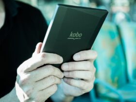 Pessoa segura um leitor digital Kobo durante uma viagem em transporte público.