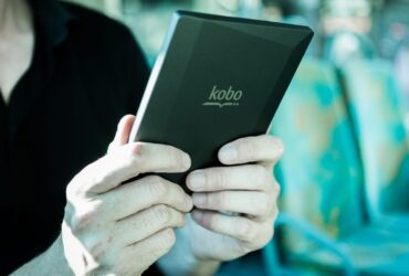 Pessoa segura um leitor digital Kobo durante uma viagem em transporte público.
