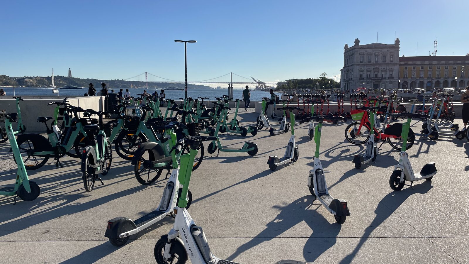 Trotinetes e bicicletas partilhadas estacionadas junto ao rio Tejo, em Lisboa.