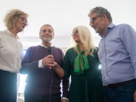 Quatro adultos participam numa sessão de karaoke com um microfone ao centro.