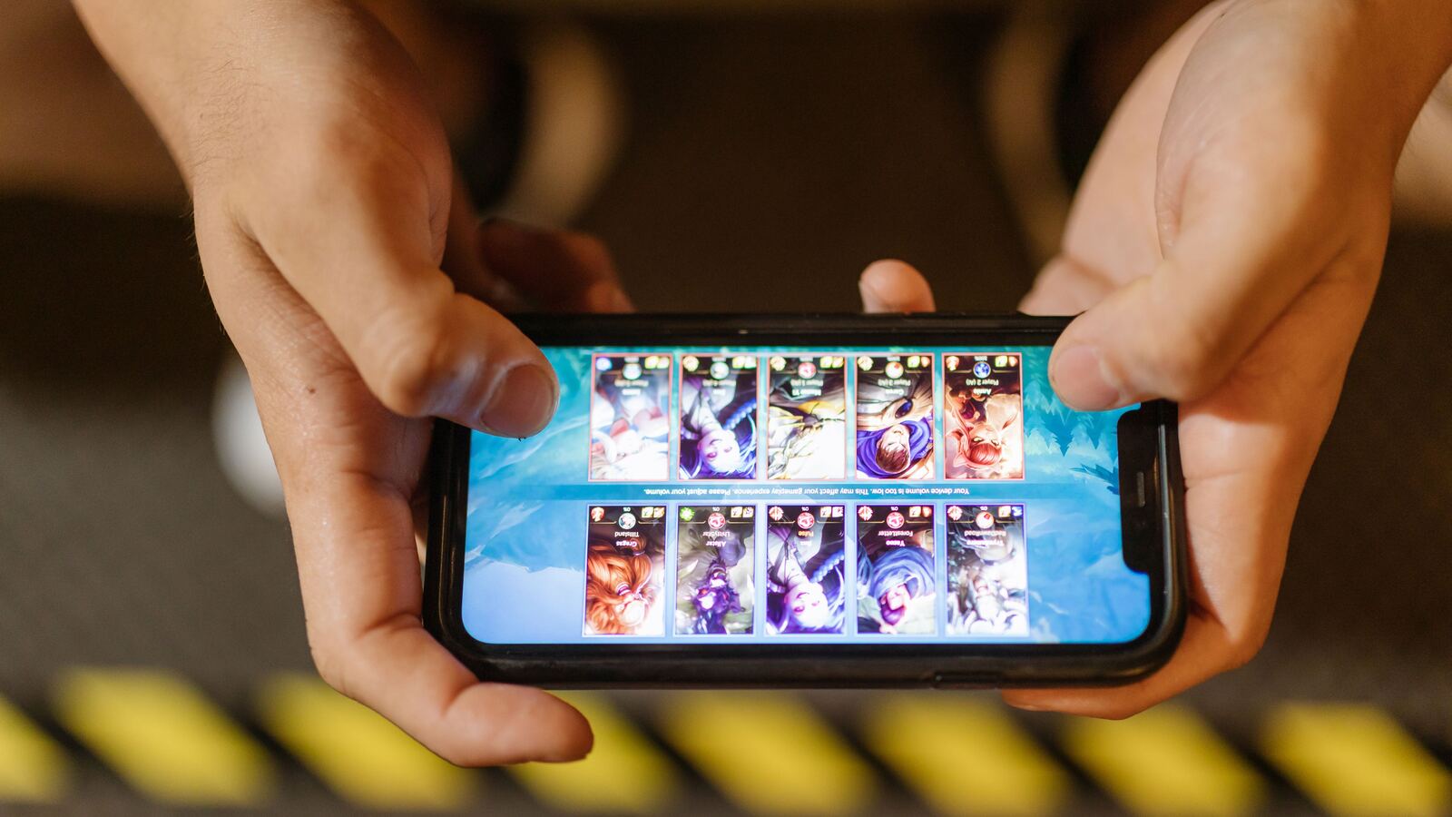 Duas mãos seguram um smartphone na horizontal durante uma partida de um jogo móvel.