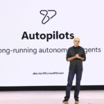 Satya Nadella fala no Microsoft Build 2026 diante de um slide sobre agentes autônomos de longa duração.