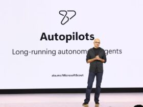 Satya Nadella fala no Microsoft Build 2026 diante de um slide sobre agentes autônomos de longa duração.