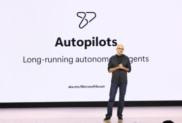 Satya Nadella fala no Microsoft Build 2026 diante de um slide sobre agentes autônomos de longa duração.