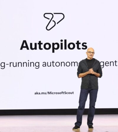Satya Nadella fala no Microsoft Build 2026 diante de um slide sobre agentes autônomos de longa duração.