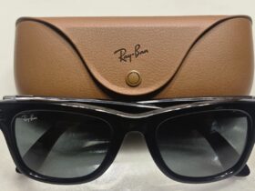 Óculos Ray-Ban Meta pretos diante do respetivo estojo de carregamento castanho.