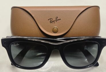 Óculos Ray-Ban Meta pretos diante do respetivo estojo de carregamento castanho.