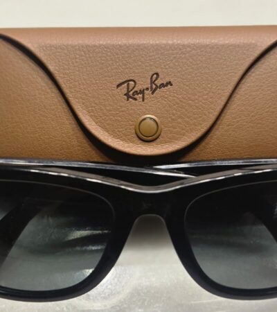 Óculos Ray-Ban Meta pretos diante do respetivo estojo de carregamento castanho.