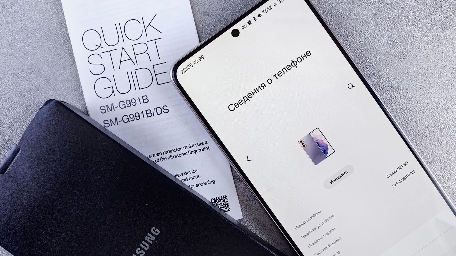 Smartphone Samsung no ecrã de informações do telefone, junto ao guia de início rápido e a uma capa preta