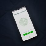 Smartphone sobre tecido escuro mostra a tela de boas-vindas do WhatsApp.
