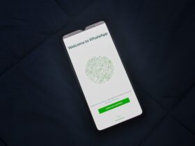 Smartphone sobre tecido escuro mostra a tela de boas-vindas do WhatsApp.