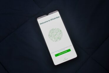 Smartphone sobre tecido escuro mostra a tela de boas-vindas do WhatsApp.