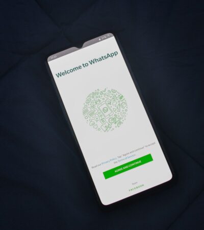 Smartphone sobre tecido escuro mostra a tela de boas-vindas do WhatsApp.