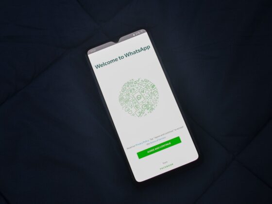 Smartphone sobre tecido escuro mostra a tela de boas-vindas do WhatsApp.
