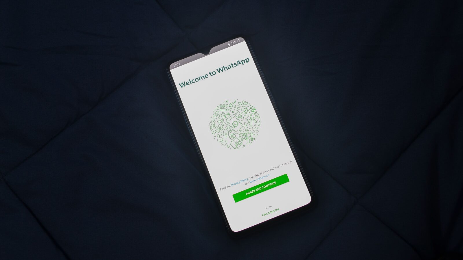 Smartphone sobre tecido escuro mostra a tela de boas-vindas do WhatsApp.